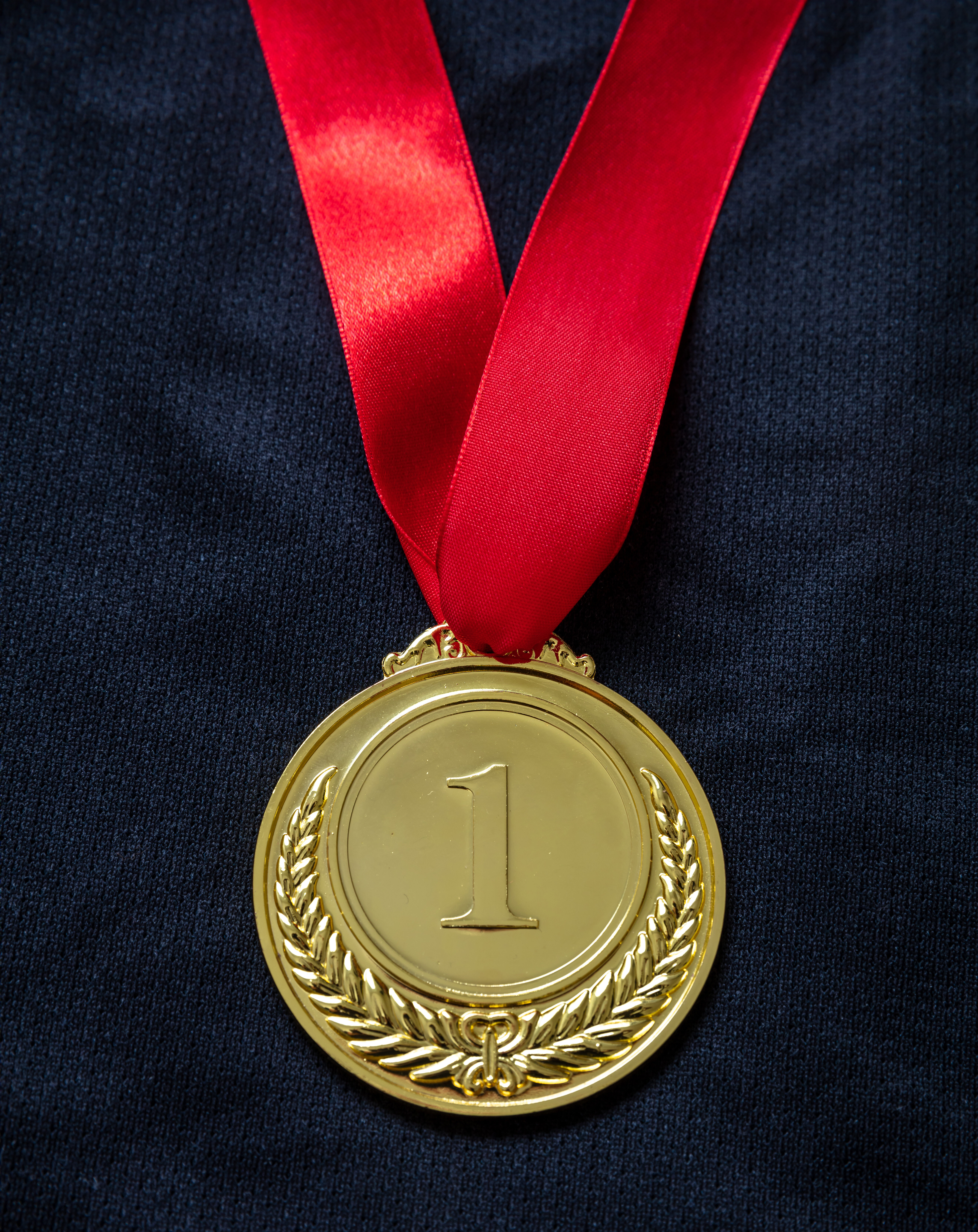 Gold medal. Champion trophy award and ribbon. Prize in sport for winner on black shirt background
